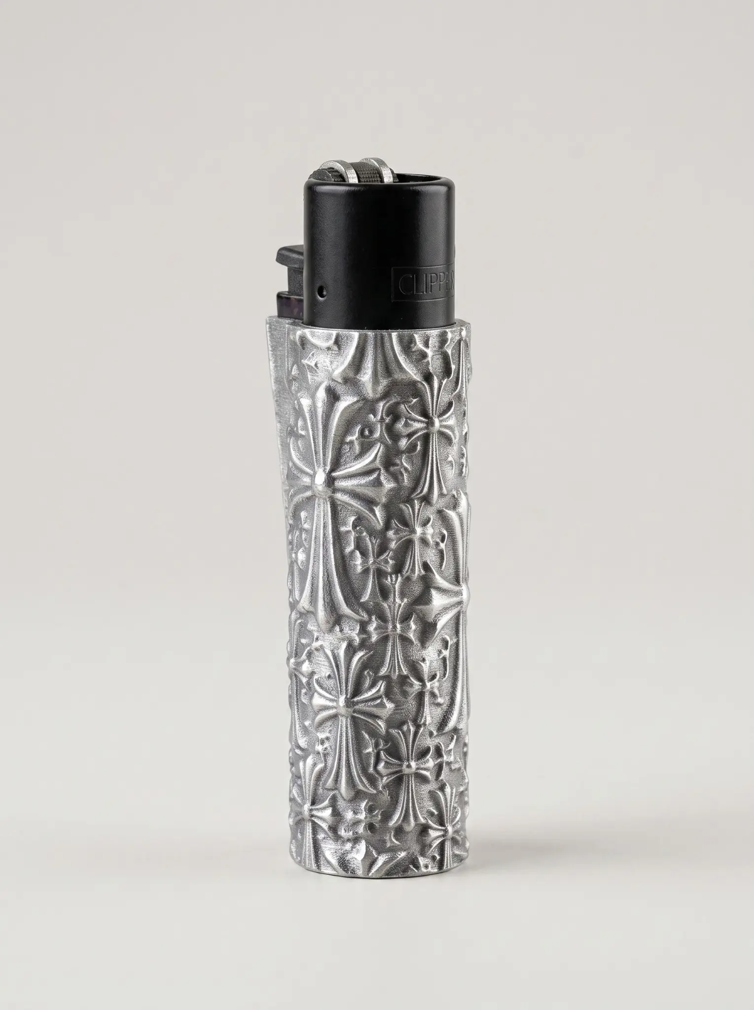 Metallic-silver cylindrical Clipper lighter sleeve with raised gothic cross relief